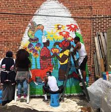 People painting a mural on brick wall